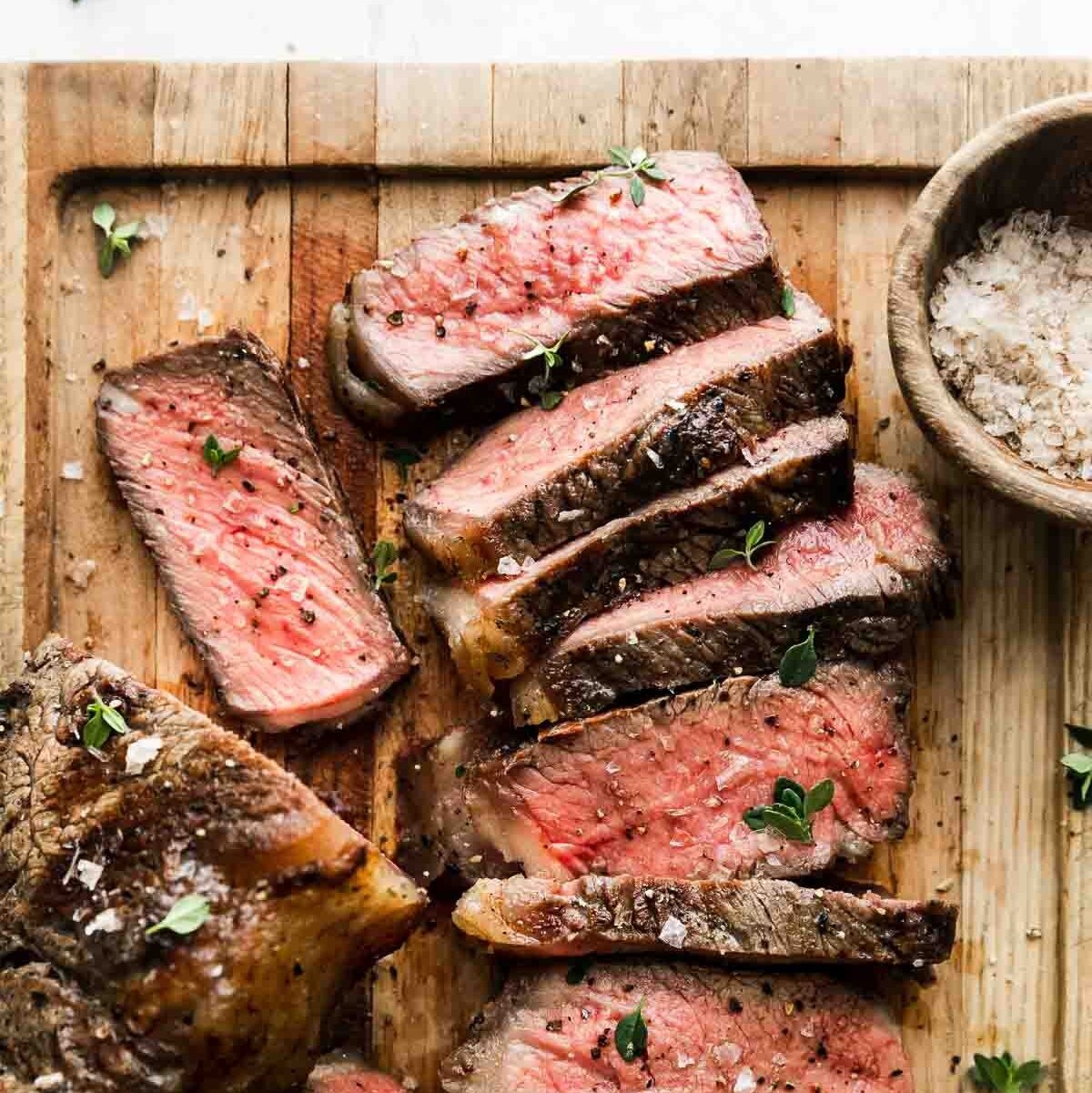 A perfectly grilled ribeye steak with a pat of melting herb butter, served with roasted asparagus and a cauliflower mash.
